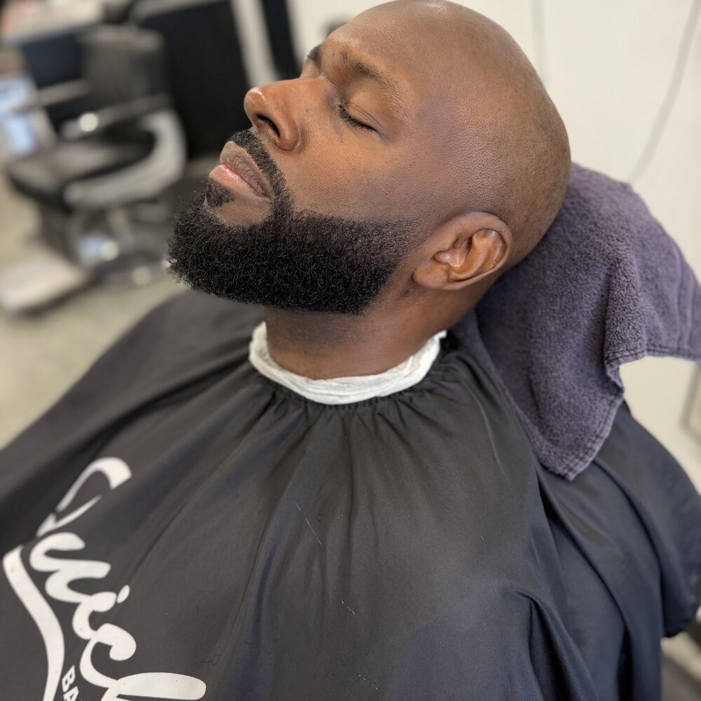 A hot towel resting at the neck before a straight razor shave
