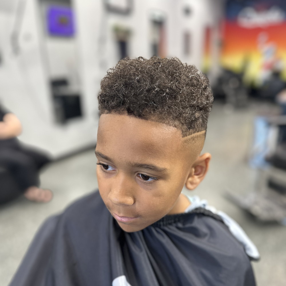 A boy with a fade, in the chair at Quicks Barbershop