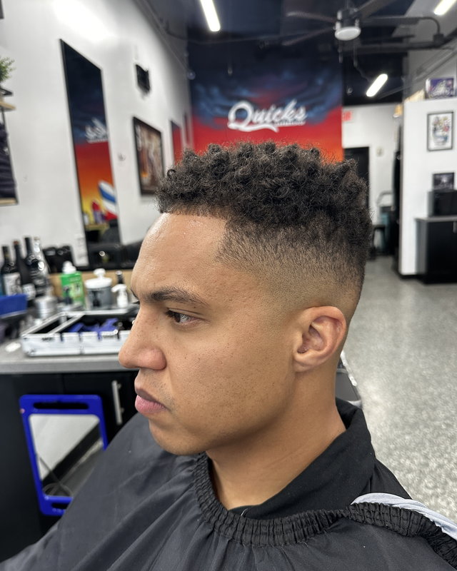 A high skin fade with the curls left long on top