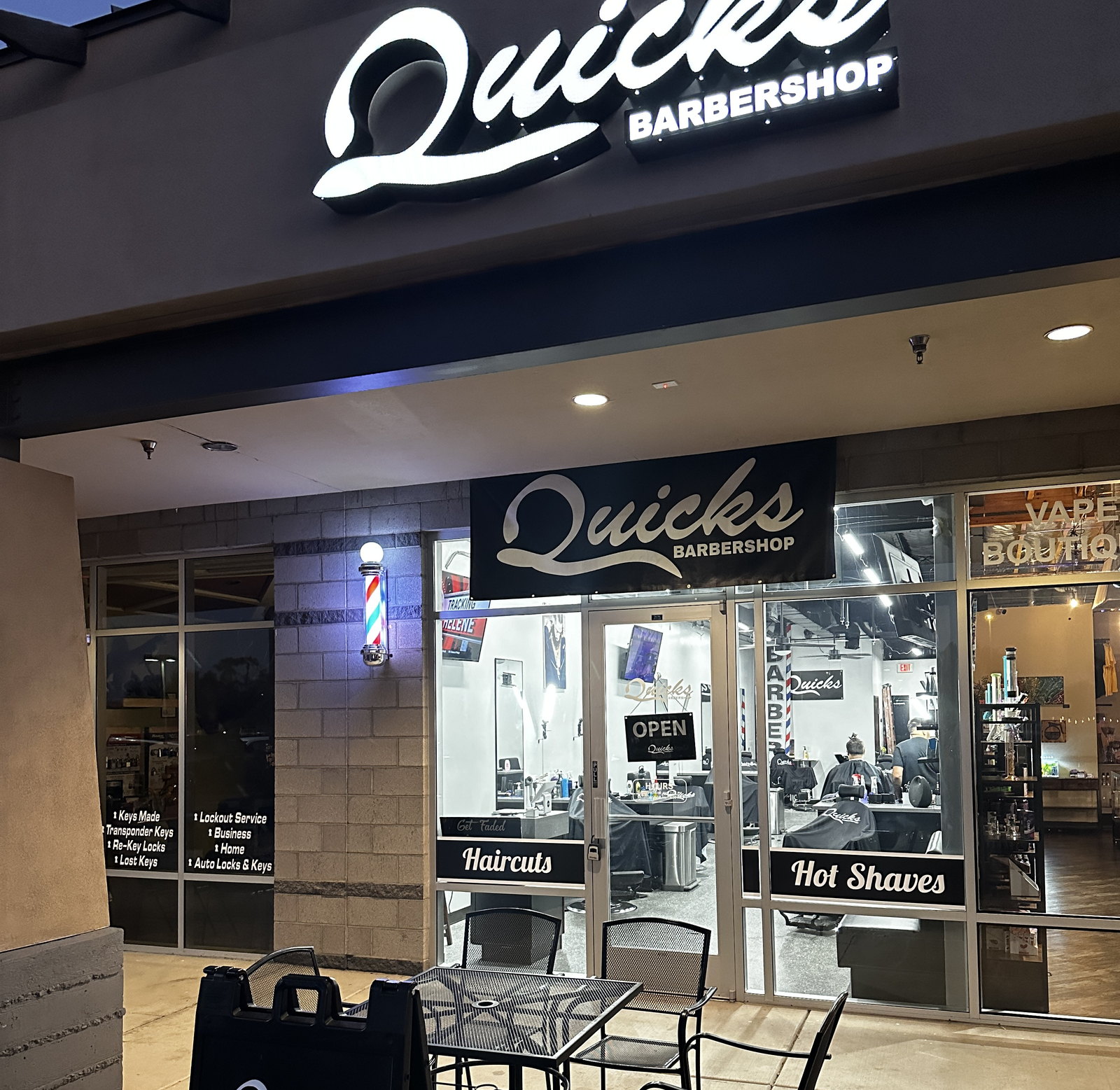 The lit Quicks Barbershop sign and entrance on Warner Road after dark