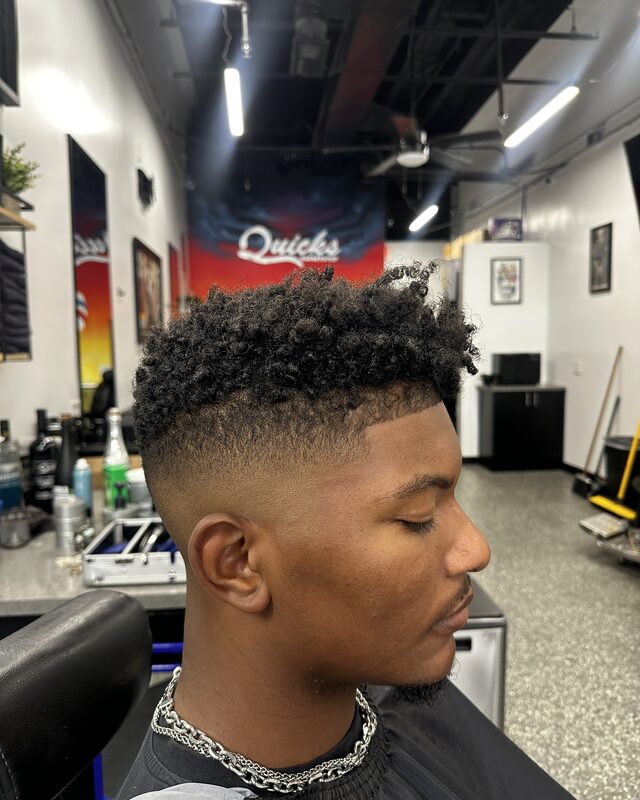 A high-top fade with tight curls left long on top